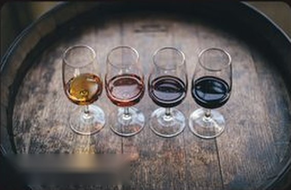 Four glasses of wine from white to deep red on a barrel top