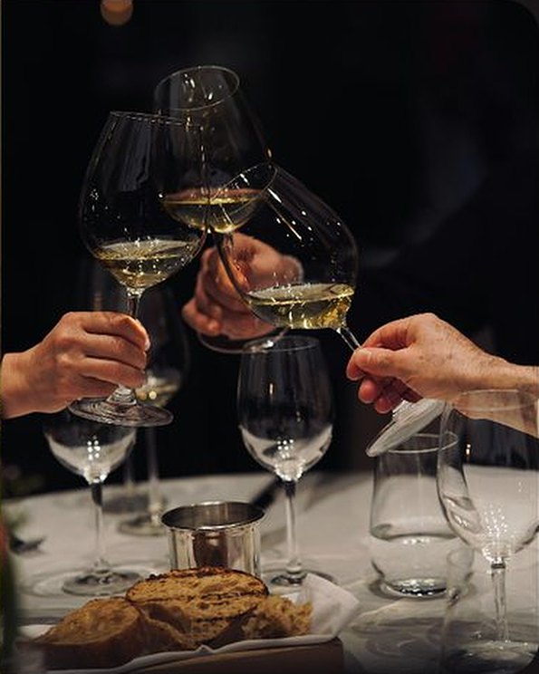 Guests toasting with glasses of white wine over dinner