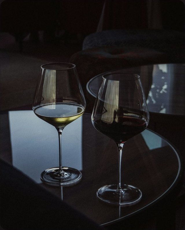 A glass of white and a glass of red wine on a dark polished table